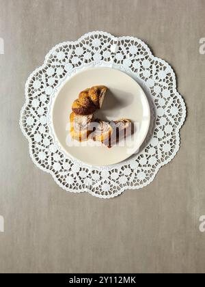 Pezzi singoli di torta di marmo serviti su un piatto bianco su un topper rotondo di carta decorativa su sfondo grigio Foto Stock