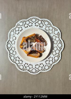 Pezzi singoli di torta di marmo serviti su un piatto bianco su un topper rotondo di carta decorativa su sfondo grigio Foto Stock