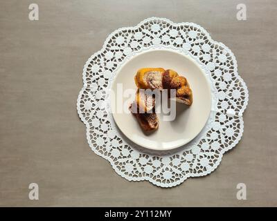 Pezzi singoli di torta di marmo serviti su un piatto bianco su un topper rotondo di carta decorativa su sfondo grigio Foto Stock