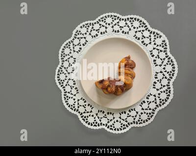 Pezzi singoli di torta di marmo serviti su un piatto bianco su un topper rotondo di carta decorativa su sfondo grigio Foto Stock