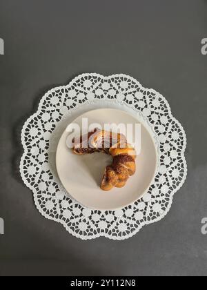 Pezzi singoli di torta di marmo serviti su un piatto bianco su un topper rotondo di carta decorativa su sfondo grigio Foto Stock