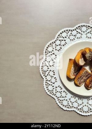 Pezzi singoli di torta di marmo serviti su un piatto bianco su un topper rotondo di carta decorativa su sfondo grigio Foto Stock