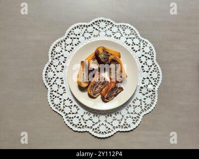 Pezzi singoli di torta di marmo serviti su un piatto bianco su un topper rotondo di carta decorativa su sfondo grigio Foto Stock