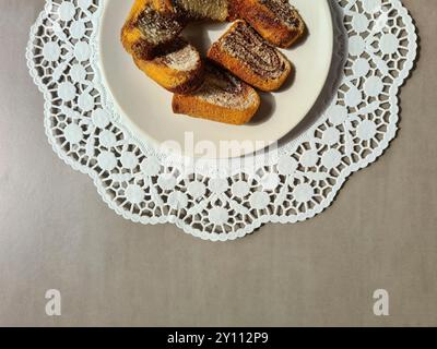 Pezzi singoli di torta di marmo serviti su un piatto bianco su un topper rotondo di carta decorativa su sfondo grigio Foto Stock