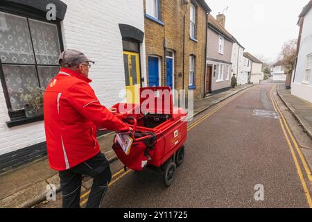 Inghilterra, Kent, Sandwich, Royal mail Postman che consegna la posta Foto Stock