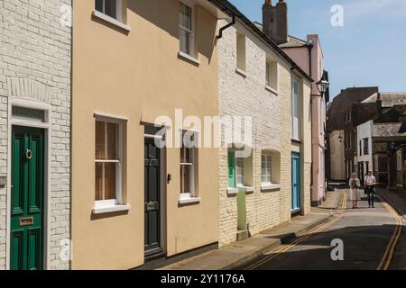 Inghilterra, Kent, Deal, coppia che mangiano pesce e patatine, camminando nella colorata strada residenziale Foto Stock