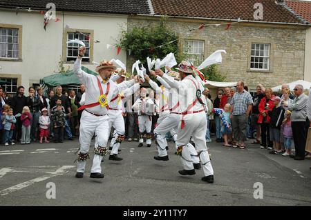 I ballerini di Morris intratterranno una folla in una fiera del villaggio di campagna a Nunney nel Somerset. Inghilterra Foto Stock