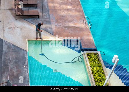 Lavoratore che pulisce una piscina per bambini, vista dall'alto. Manutenzione e cura della piscina. Foto Stock