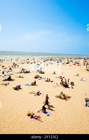 Gli amanti della spiaggia si rilassano su una spiaggia di sabbia durante una giornata estiva soleggiata, si fanno un tuffo nel calore e si godono le vacanze Foto Stock