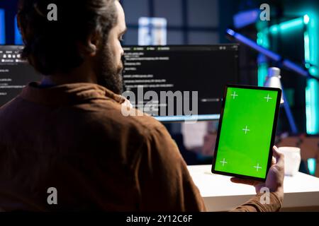 Programmatore che progetta e sviluppa applicazioni software utilizzando un tablet con schermo verde. Amministratore IT che implementa e gestisce i sistemi aziendali utilizzando un dispositivo Chroma Key Foto Stock