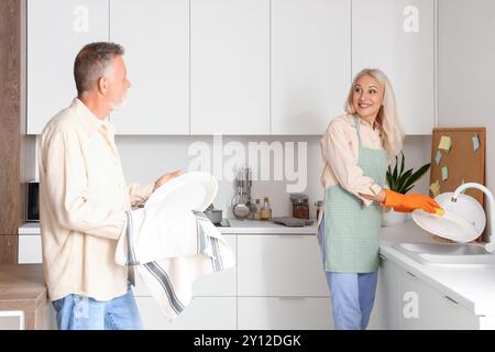 I piatti in cucina vengono lavati da una coppia matura Foto Stock