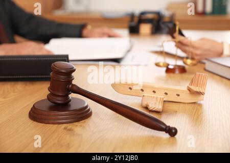 Il martelletto del giudice con l'aereo di legno sul tavolo dell'avvocato durante la riunione in ufficio, primo piano Foto Stock