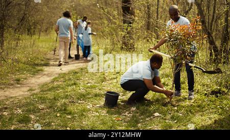 Attivisti afroamericani piantano alberi per la conservazione della natura, contribuendo alla sostenibilità e alla conservazione dell'ecosistema. Team di volontari che si uniscono per la cura dell'ambiente, semi di piante. Telecamera B.. Foto Stock