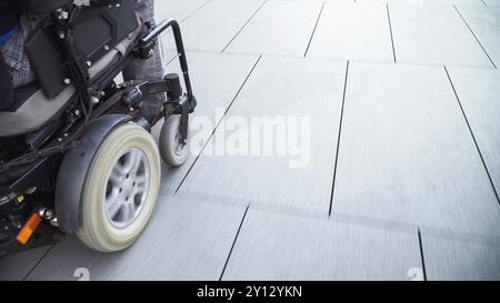 Uomo su sedia a rotelle elettrica che utilizza una rampa. Concetto di accessibilità Foto Stock