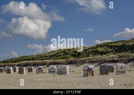 Sedie a sdraio su una spiaggia sabbiosa di fronte a uno sfondo di dune in una giornata leggermente nuvolosa, spiekeroog, frisia orientale, mare settentrionale, germania Foto Stock