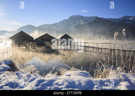 Baite al mattino davanti a montagne, lago, neve, inverno, nebbia, lago Kochel, colline alpine, Baviera, Germania, Europa Foto Stock