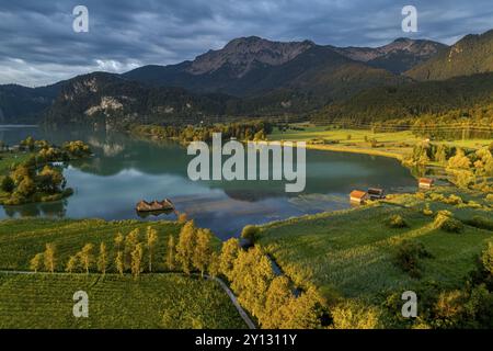 Vista aerea di un lago di fronte alle montagne, alba, primavera, nuvole scure, lago Kochel, ai piedi delle Alpi, Baviera, Germania, Europa Foto Stock