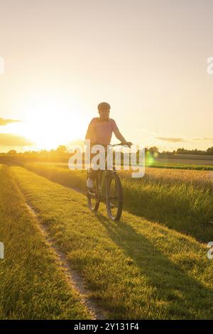 Un ciclista cavalca su una pista sterrata attraverso il paesaggio naturale al tramonto, Gechingen, Foresta Nera, Germania, Europa Foto Stock