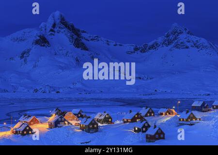 Insediamento Inuit, case nella neve profonda di fronte alle montagne, ora blu, crepuscolo, inverno, Tasiilaq, Groenlandia orientale, Groenlandia, Nord America Foto Stock