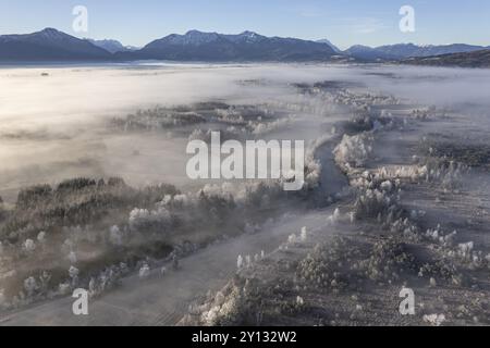 Vista aerea di un paesaggio brughiale con fiume di fronte alle montagne in inverno, hoarfrost, luce del mattino, vista delle Alpi bavaresi, Loisach, colline alpine Foto Stock