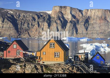 Tipiche case groenlandesi di fronte agli iceberg, insediamento Inuit, estate, sole, Uummannaq, Groenlandia occidentale, Groenlandia, Nord America Foto Stock