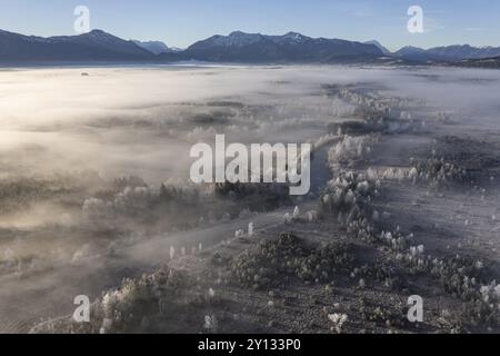 Vista aerea di un paesaggio brughiale con fiume di fronte alle montagne in inverno, hoarfrost, luce del mattino, vista delle Alpi bavaresi, Loisach, colline alpine Foto Stock