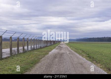 Lunga strada di campagna che si estende oltre un albero solitario fino all'orizzonte lontano Foto Stock