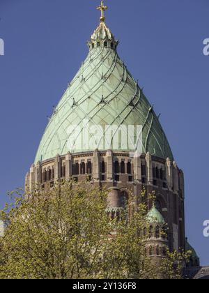 Grande guglia verde della chiesa vicino a alberi in fiore sotto un cielo limpido, haarlem, paesi bassi Foto Stock