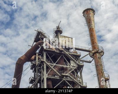 Vista dettagliata di un impianto industriale abbandonato con torri arrugginite e strutture metalliche di fronte a un cielo nuvoloso, Duisburg, regione della Ruhr, Germania, Europa Foto Stock