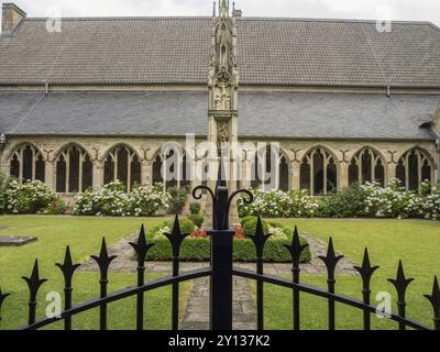 Un cortile ben tenuto con architettura gotica, aiuole di fiori e una recinzione decorativa in primo piano, xanten, basso reno, germania Foto Stock