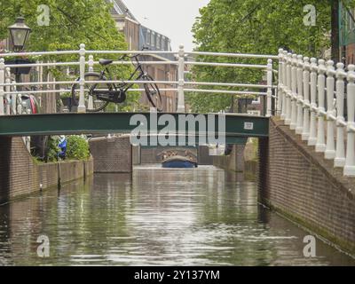 Un ponte su un canale con una bicicletta su di esso, tipico paesaggio urbano in una giornata di pioggia a Leida, Paesi Bassi Foto Stock