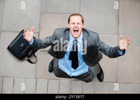 Uomo d'affari arrabbiato, cielo o frustrato che urla in città con stress, ansia e problemi di perdita di lavoro. Sopra, licenziato o infelice commerciante di azioni che grida con Foto Stock