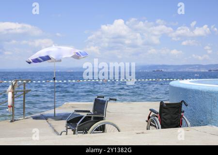 Sedie a rotelle su una spiaggia accessibile con sedia a rotelle per il trasporto di persone con disabilità in acqua Foto Stock