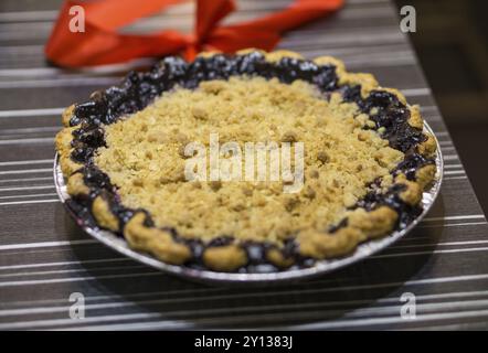 Bella torta di noci pecan su una superficie di legno circondata da noci pecan intere e conchiglie pecan. Torta in stile americano Foto Stock