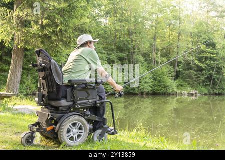 Giovane uomo in una sedia a rotelle che pesca Foto Stock