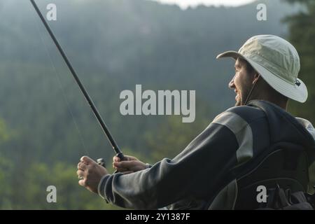 Giovane uomo in una sedia a rotelle che pesca Foto Stock