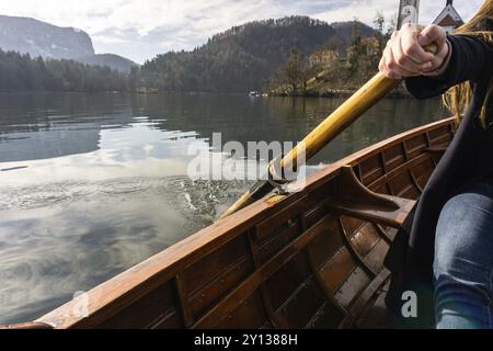 Giovane donna che usa la pagaia su una barca di legno, il lago di Bled in Slovenia remando su barche di legno in una giornata di sole Foto Stock