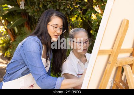 Dipingere su tela, la nipote asiatica e la nonna si godono attività artistiche all'aperto Foto Stock