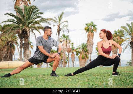 Una giovane coppia atletica che allunga i muscoli con pose yoga dopo un allenamento sulla costa. Due persone sportive che si godono una sessione di Pilates all'aperto per migliorare la loro salute e flessibilità. Foto di alta qualità Foto Stock