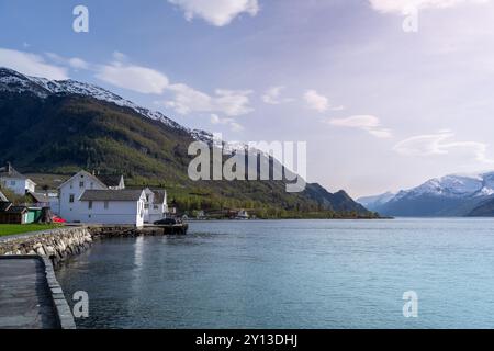 Un tranquillo villaggio adagiato sulla costa dell'Hardangerfjord. Il contrasto tra le case bianche e le calme acque turchesi è impressionante. Voss, Foto Stock