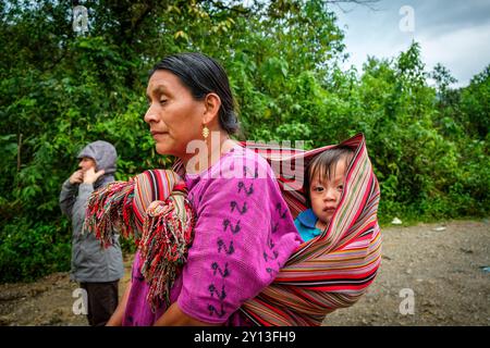 Bambino trasportato in una gonna tradizionale, piscine Ha' Kok, fiume Tortuga, Lancetillo - la Parroquia, Northern Transversal Strip, Quiché Department, Guatemala. Foto Stock