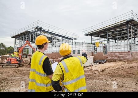 operai edili in cantiere che indossano indumenti protettivi Foto Stock