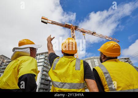 operai edili in cantiere che indossano indumenti protettivi Foto Stock