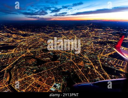 Vista aerea di Mosca, Russia, con strade illuminate all'ora blu - motore dell'aereo e ala con aletta visibile in basso a destra Foto Stock