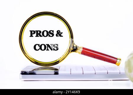 Messaggi PRO e CONTRO attraverso una lente d'ingrandimento, primo piano su una calcolatrice davanti a uno sfondo chiaro Foto Stock