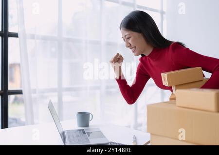 Una donna, venditrice online, raggiunge il successo delle vendite utilizzando un tablet, gli obiettivi e favorisce il successo nella sua attività di e-commerce. Foto Stock