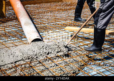 Lavoratore che distribuisce calcestruzzo su Rebar Framework per Slab Foundation Construction Foto Stock