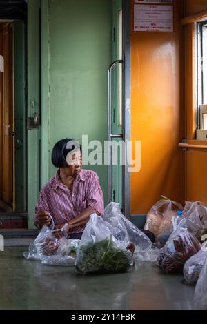 31 agosto 2024, Nakhon Pathom, Thailandia: Si vede una donna anziana che prepara alcuni sacchi di verdure, a terra, all'interno di un vagone ferroviario, nella provincia di Nakhon Pathom, in Thailandia. La provincia di Nakhon Pathom, a ovest di Bangkok, è una delle città più antiche della Thailandia, con terre fertili che supportano una varietà di colture, tra cui riso, noci di cocco e canna da zucchero, rendendo l'agricoltura una parte vitale dell'economia locale. (Immagine di credito: © Nathalie Jamois/SOPA Images via ZUMA Press Wire) SOLO PER USO EDITORIALE! Non per USO commerciale! Foto Stock