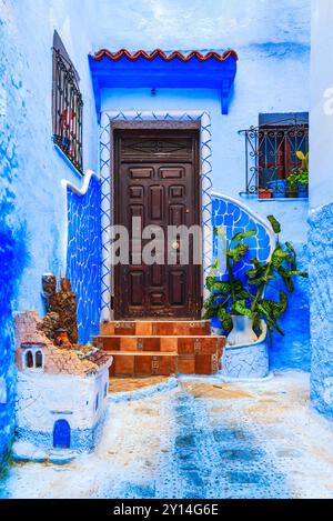 Chefchaouen, Marocco. Scala e parete blu decorate con vasi di fiori colorati, destinazione turistica del Nord Africa. Foto Stock