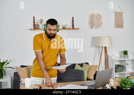 Un uomo esamina i documenti mentre indossa le cuffie, concentrandosi sulle sue attività a casa. Foto Stock